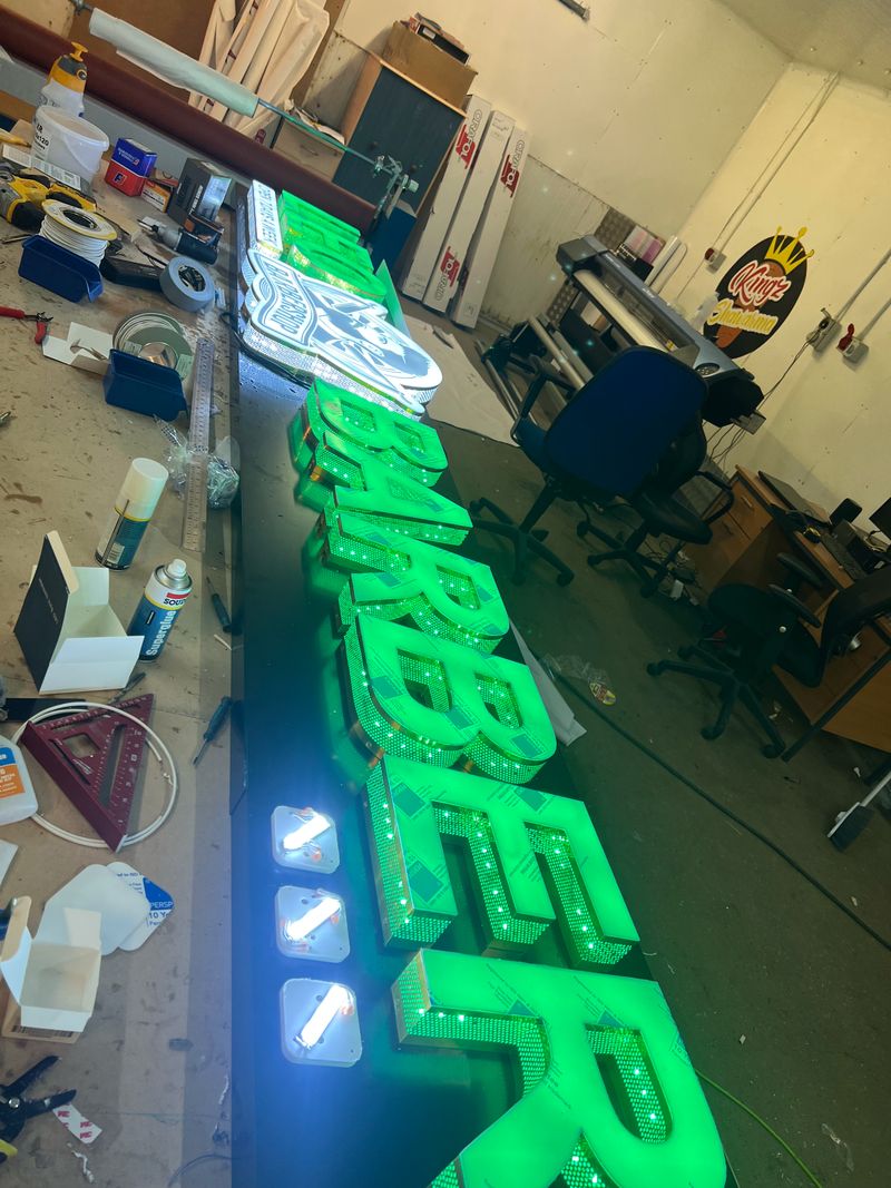 Green built-up illuminated 3D letters spelling Barber
