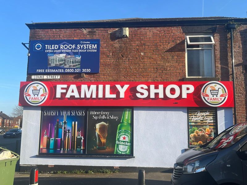 Large red and white fascia sign with product graphics for a family shop