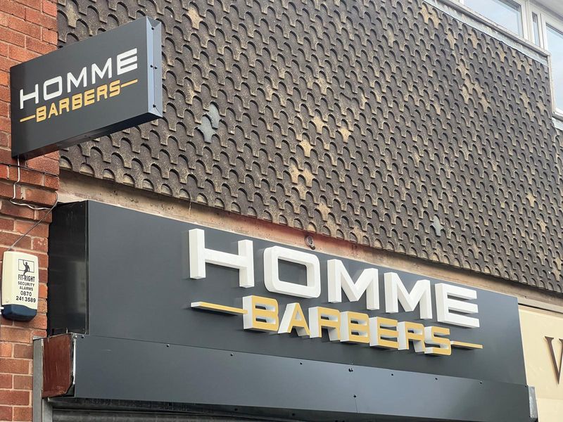Modern black and gold Homme Barbers shopfront signage