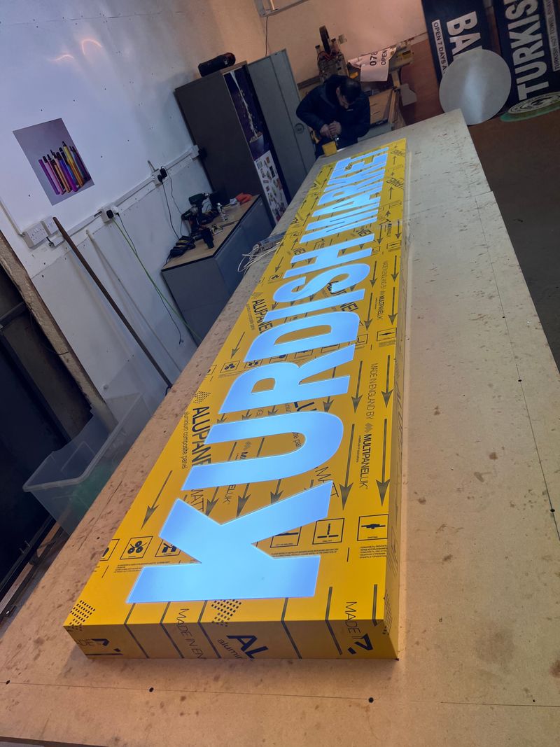 Yellow illuminated shop fascia for a Kurdish market