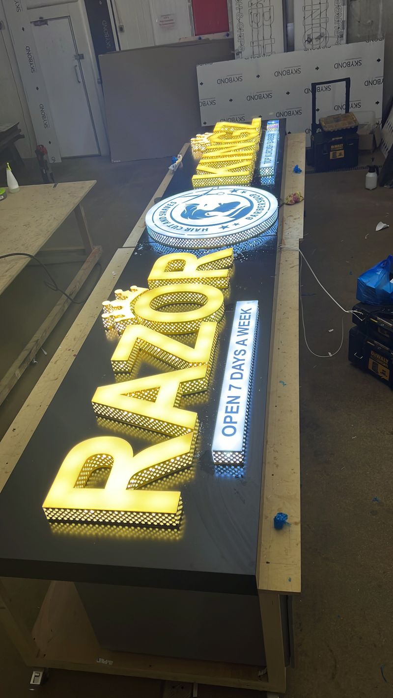 Illuminated blue and gold fascia sign for Razor Barbers