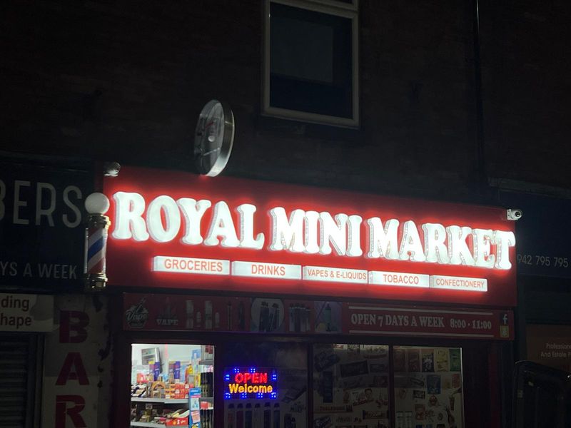 Red illuminated shop sign for Royal Mini Market glowing at night