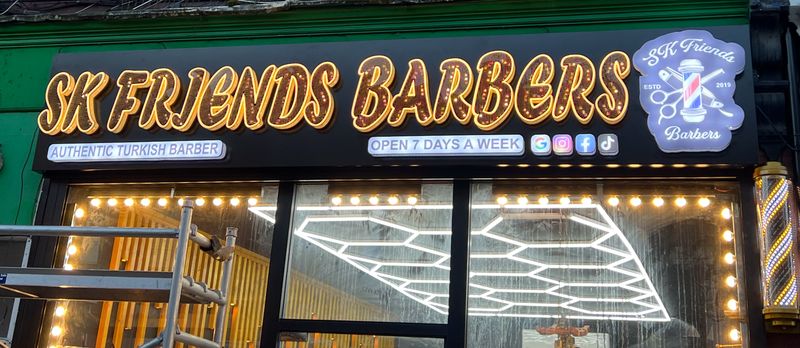 Illuminated green shopfront sign for SK Friends Barbers