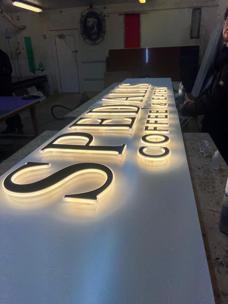 Warm halo-lit built-up letters reading Spedals Coffee & Eatery
